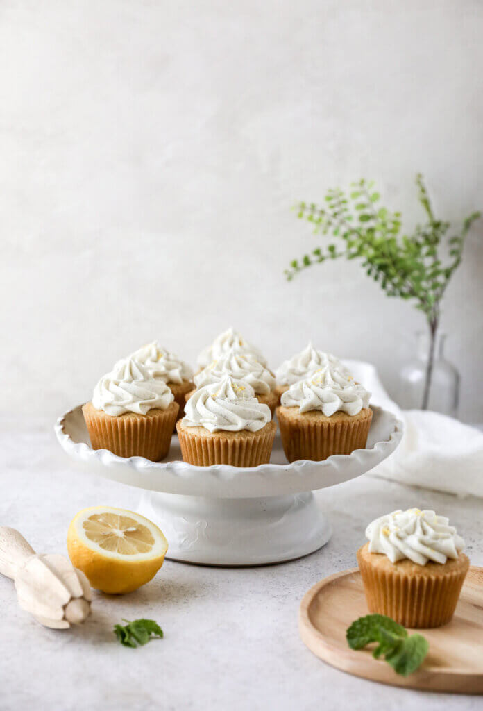 A cake stand with gluten-free lemon cupcakes with another side plate with a lemon cupcake and a sprig of mint. 