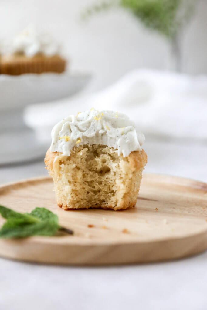 Straight on view of a lemon cupcake with a bite taken out of it. 