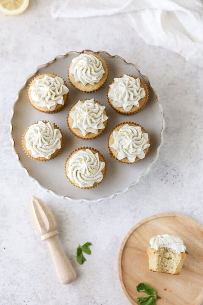 A top down view of a cake stand with frosted lemon cupcakes. 